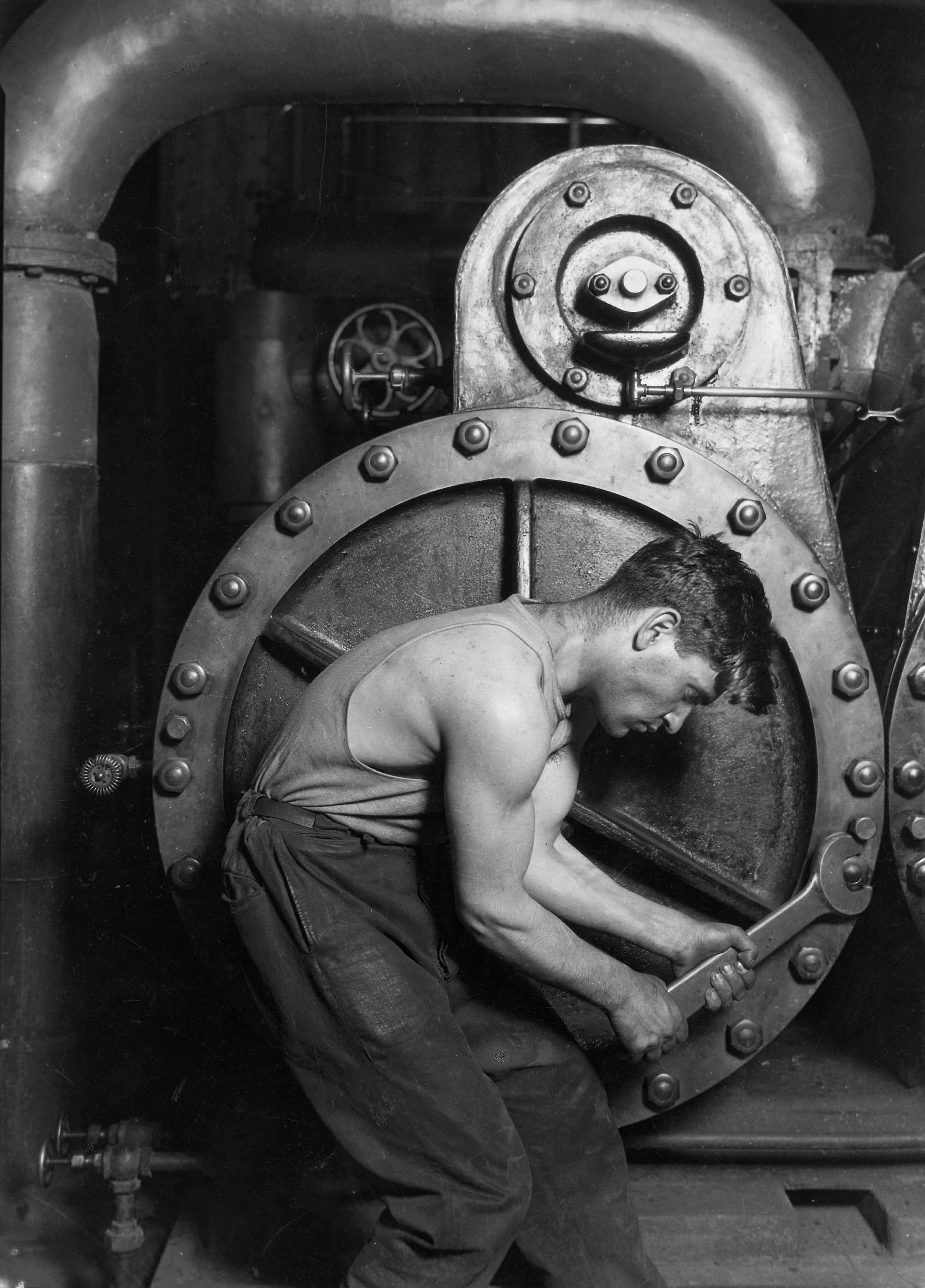 Lewis Hine, Power House Mechanic Working on Steam Pump (1920) &mdash; figure bent into the machine, the work done in close.