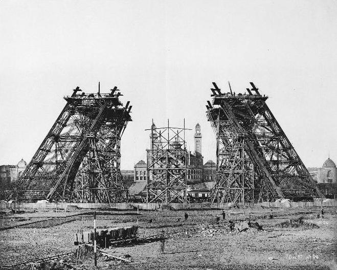 Construction of the Eiffel Tower, December 1887 — iron framework rising from temporary scaffolding, the foundation of a new shape going down.