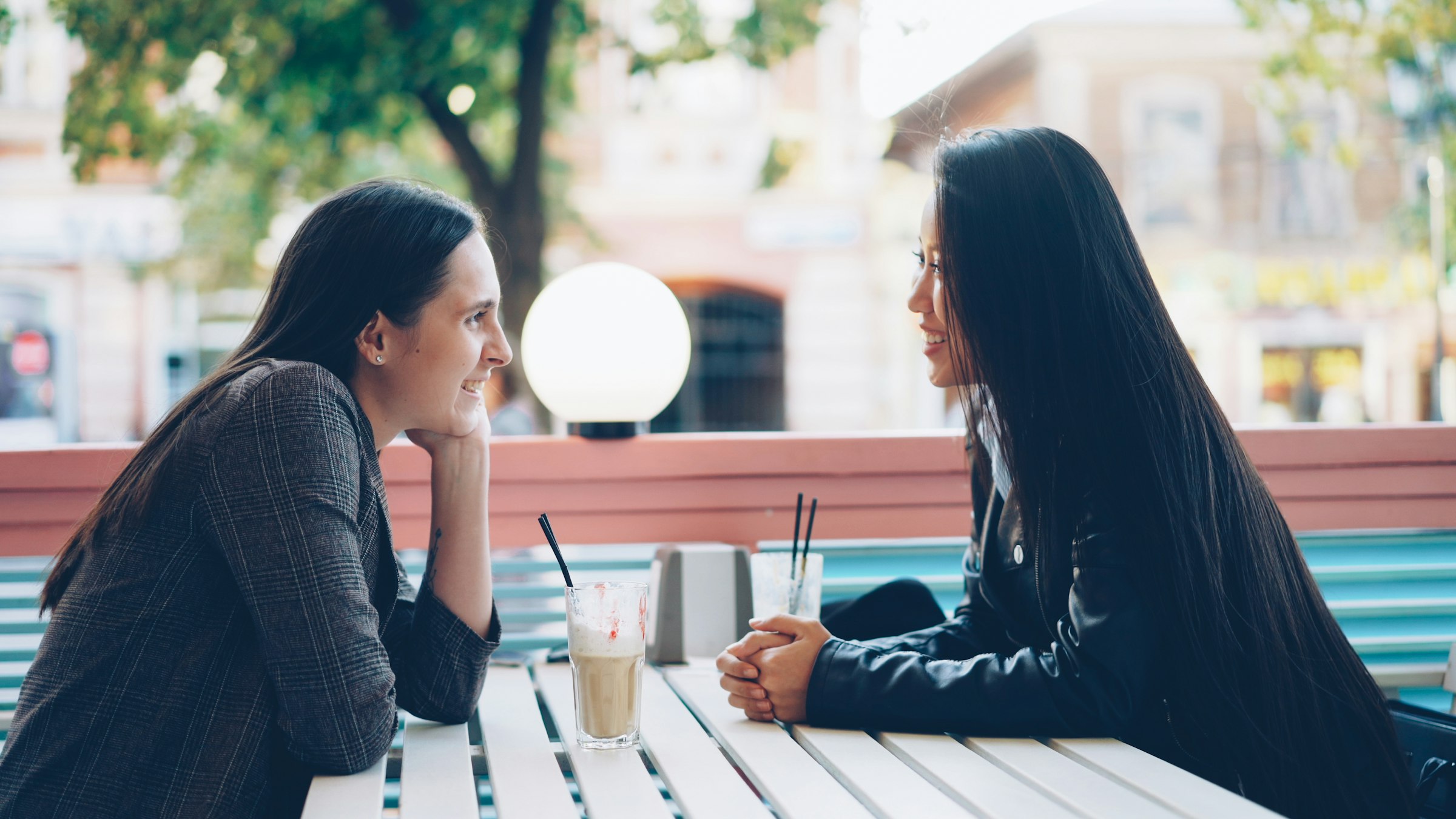 A coffee on a table, both hands wrapped around it, ordinary morning light.